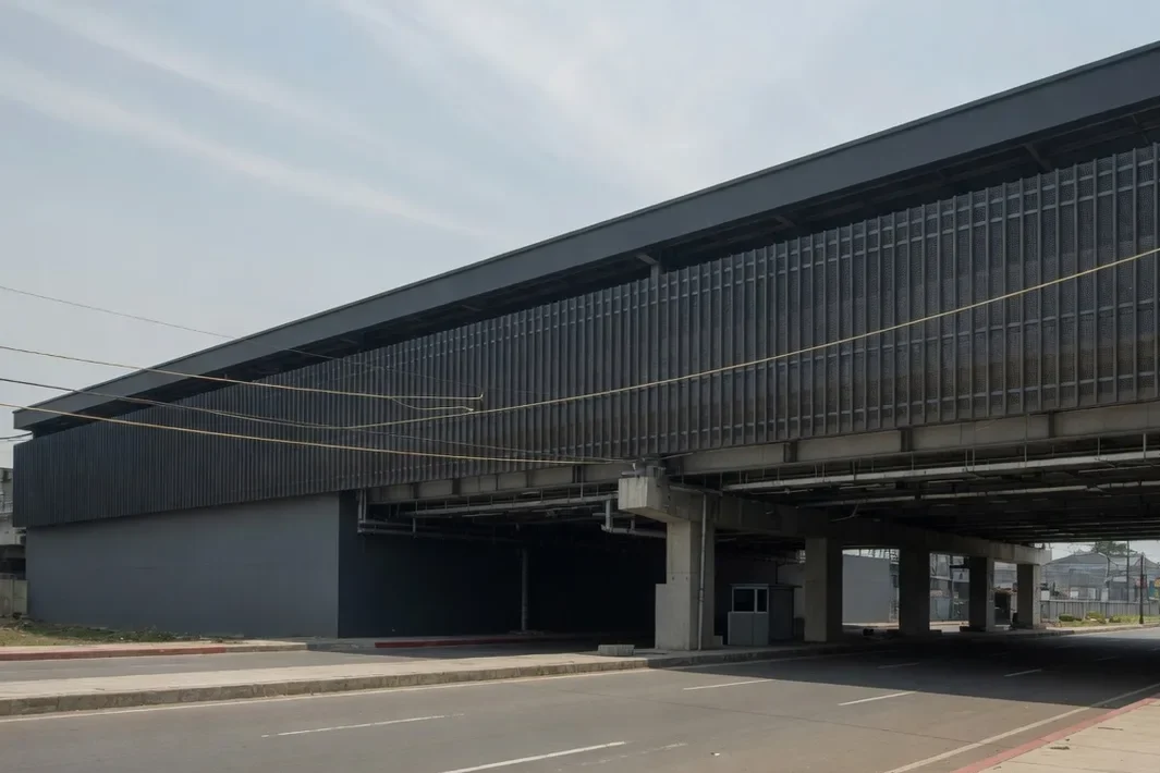 Station élevée sombre, avec un écran de métal, une rue et des fils.
