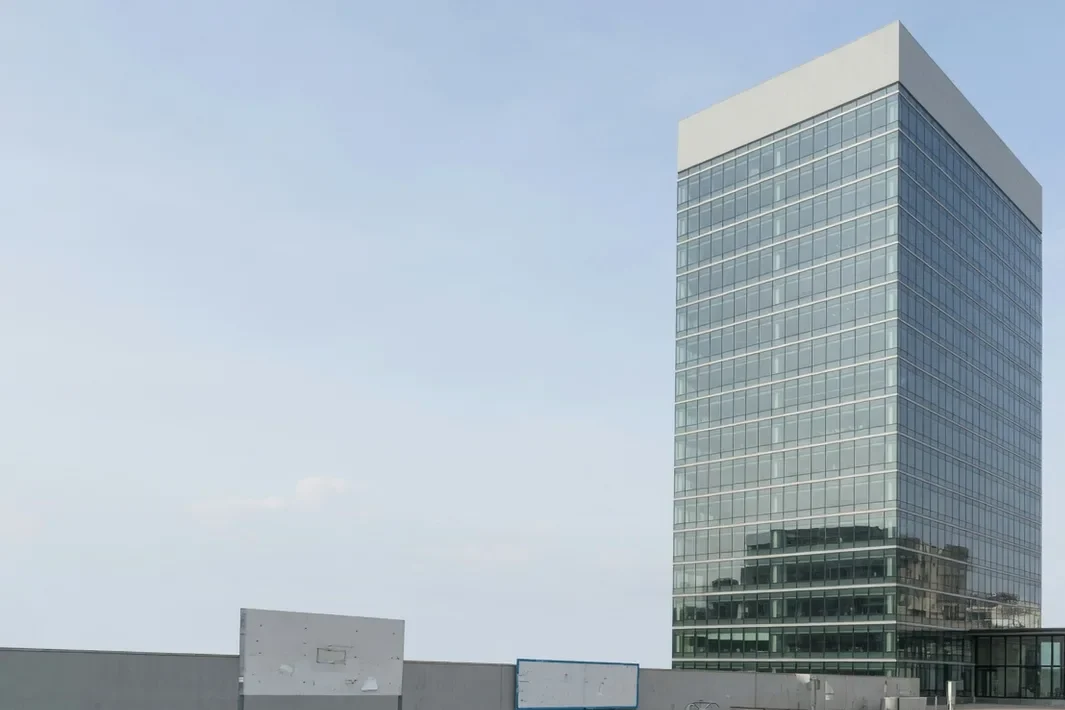 A torre de vidro à direita, com a coroa fina e o céu azul claro no meio.