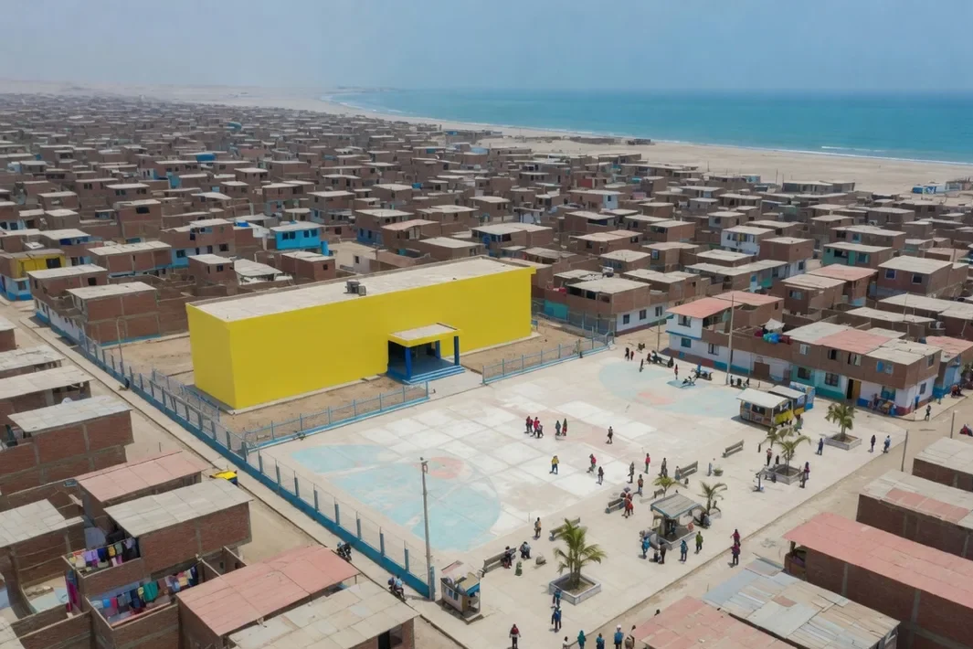 Vista aérea de um bairro de casas baixas de tijolo até o mar, com uma escola amarela e azul.