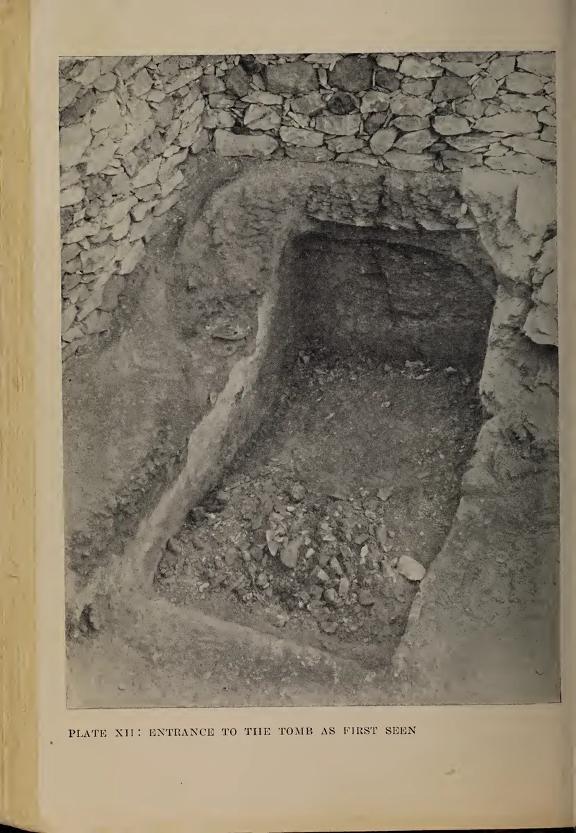 Página com fotografia antiga de uma entrada escavada entre pedras, conservando a legenda da prancha XII.