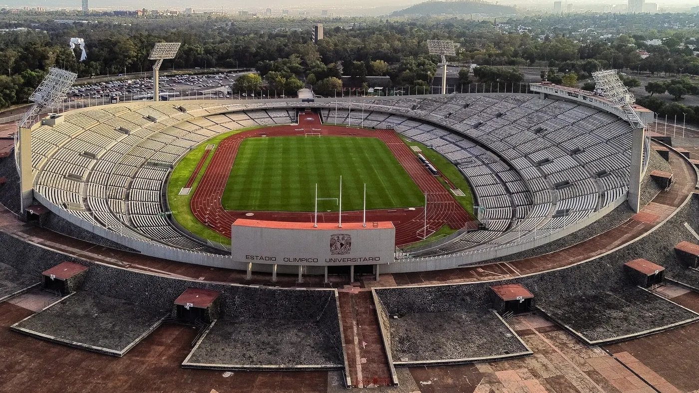 Vista aérea de um estádio oval vazio, com o nome do estádio escrito na arquibancada.