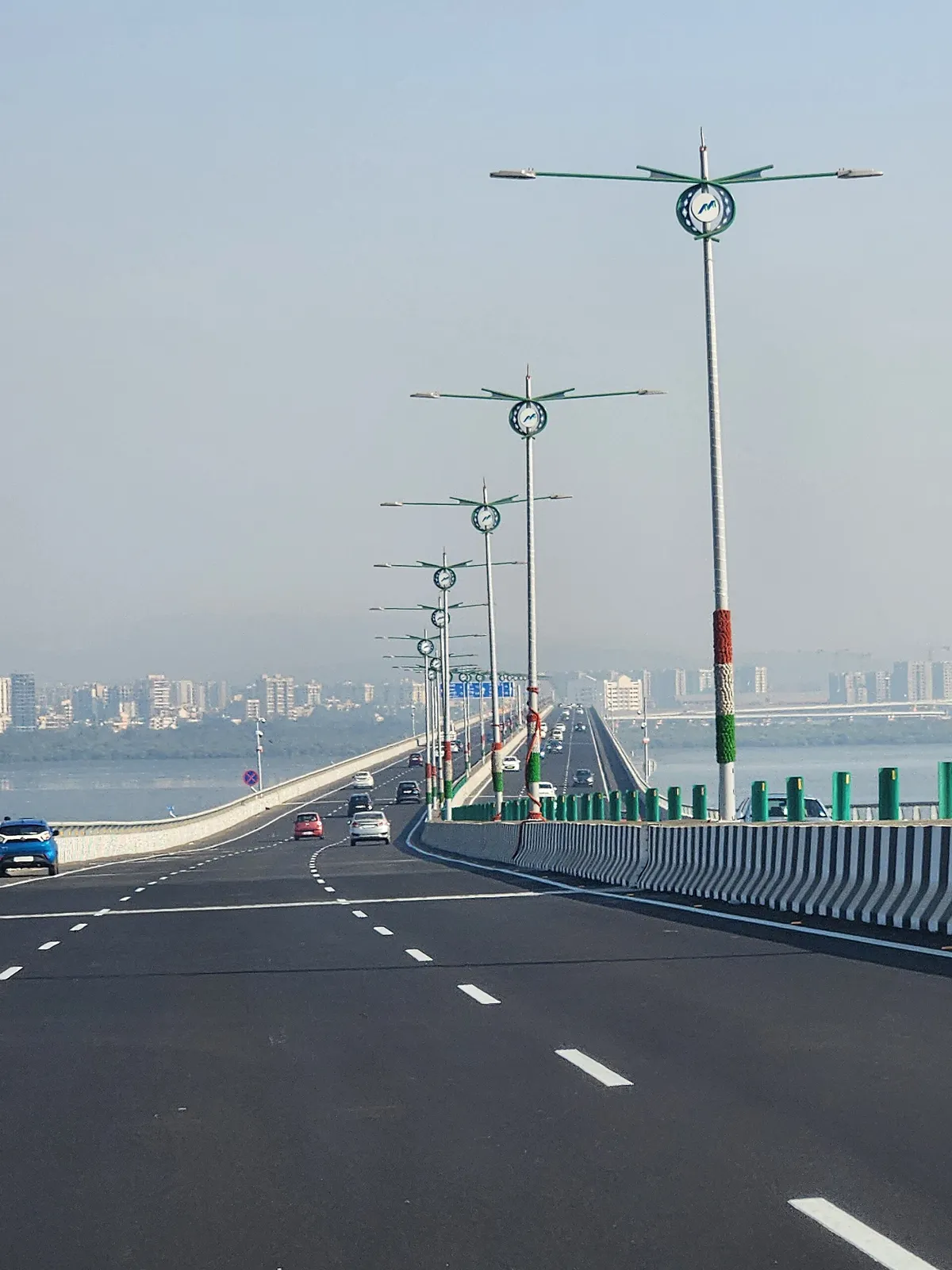 Uma ponte sobre a água, com a via e uma fileira de postes verdes e brancos.
