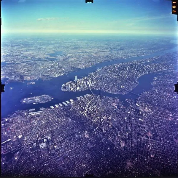 Photographie aérienne oblique de Manhattan, d’îles, de fleuves et de quartiers avec ponts ; bords du film et numéro 109 visibles.