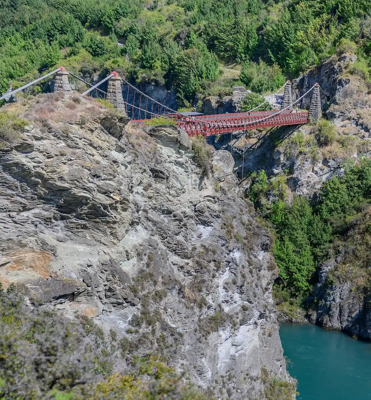 A ponte vermelha do Kawarau sobre o desfiladeiro, com o rio azul embaixo.