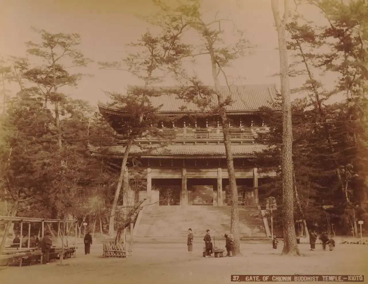 O grande portão de madeira do templo Chion-in, em Quioto, cercado por pinheiros, com visitantes de quimono na escadaria.