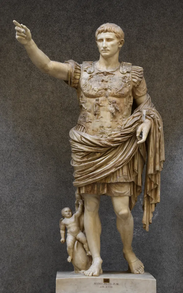 Estátua de mármore de Augusto, com braço levantado, couraça em relevo e pequeno Cupido junto à perna.