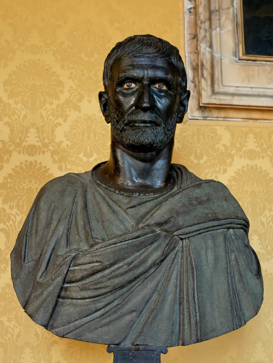 Busto de bronze conhecido como Bruto Capitolino, com barba, olhos incrustados e pregas da roupa.