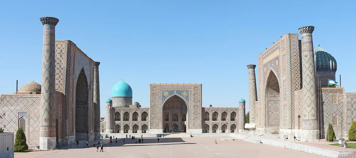 Três fachadas de azulejo e minaretes em volta da praça, com o céu azul no meio.