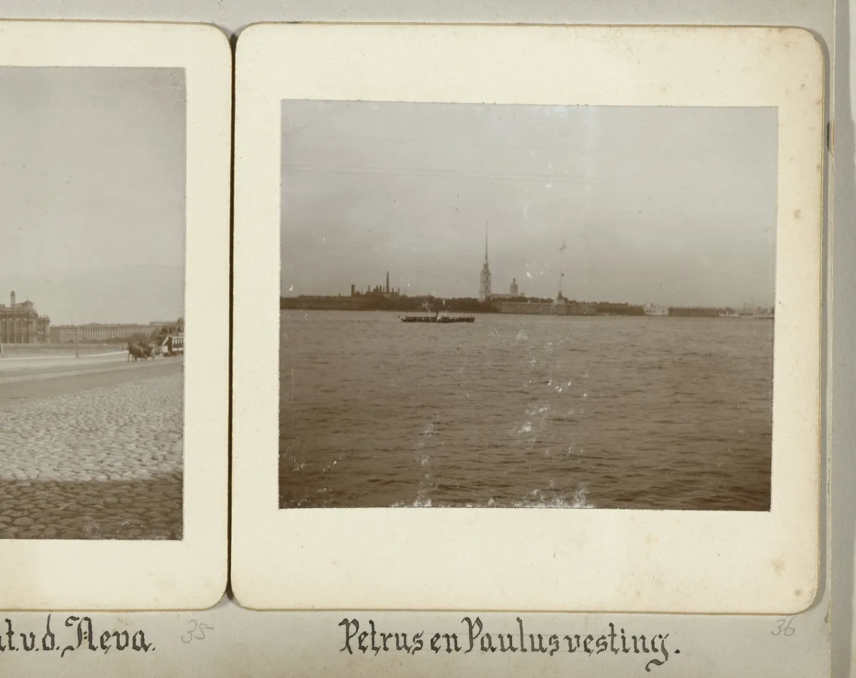 Página de álbum com fotografia da fortaleza além do rio Neva, agulha da catedral, embarcação e legenda manuscrita; fragmento de outra fotografia à esquerda.