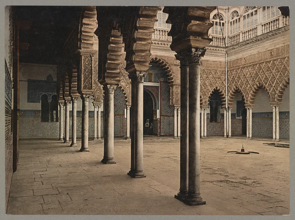 Pátio com arcadas ornamentadas, colunas, galerias superiores e piso pavimentado, em fotocromo com borda e título.