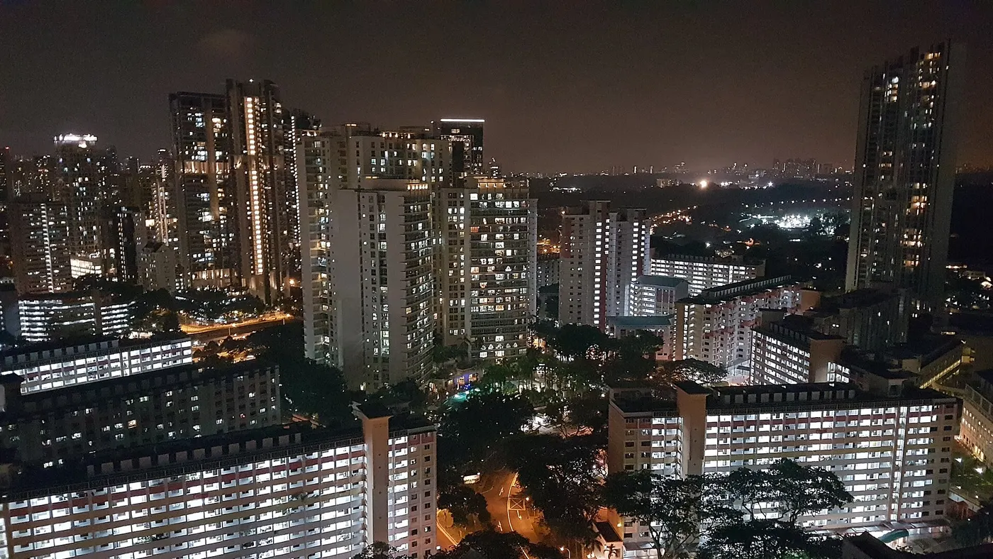Blocos residenciais altos à noite, com janelas acesas e sem rostos.