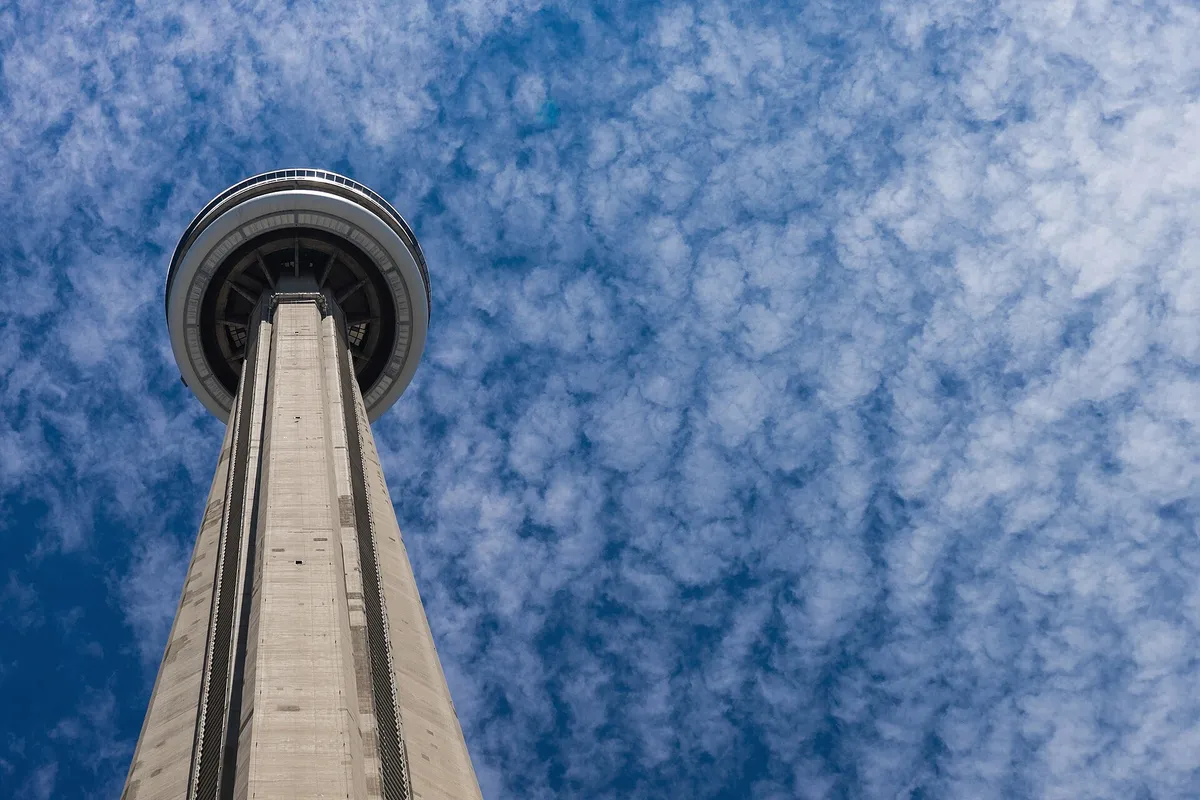 El fuste de hormigón de la CN Tower y el anillo del mirador contra un cielo azul con nubes.