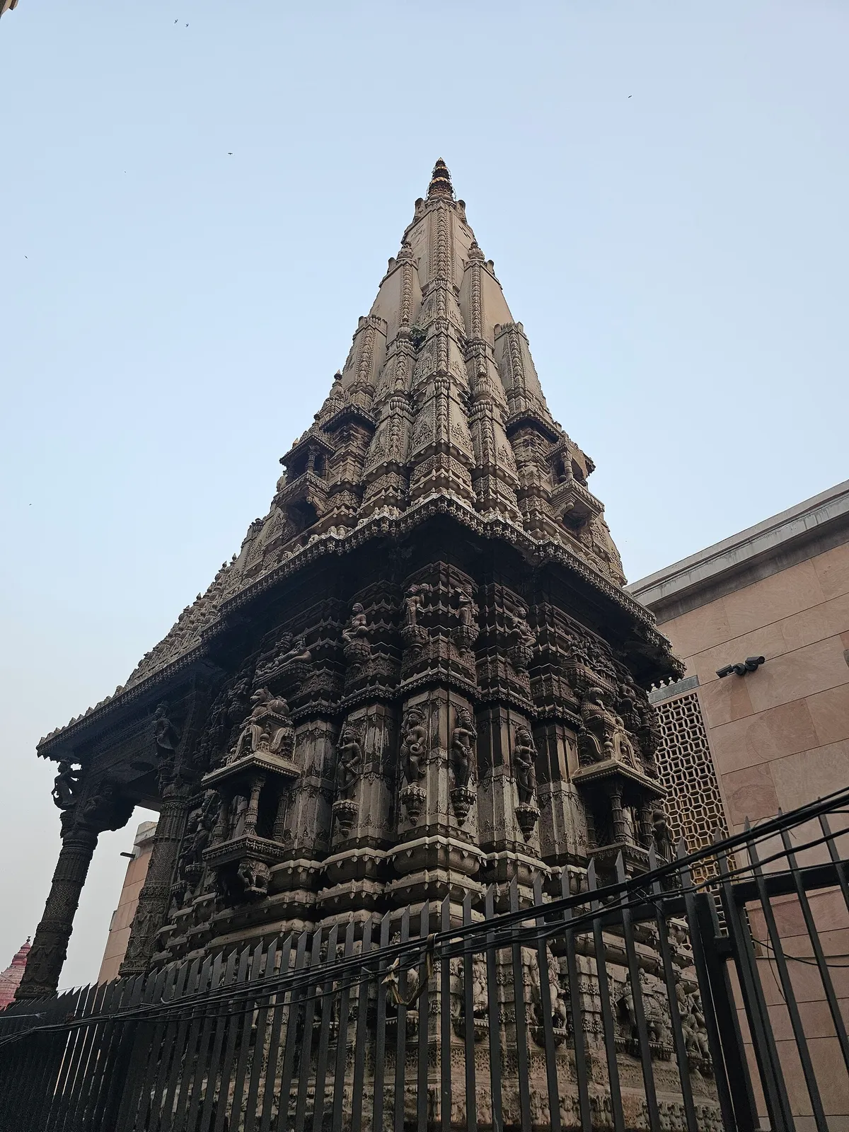 Torre de pedra esculpida do templo, atrás de uma grade escura.
