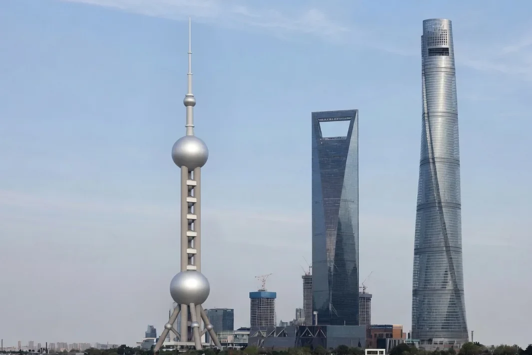O horizonte de Pudong, com a torre de esferas, a torre abridor e a torre torcida, sobre a água clara.
