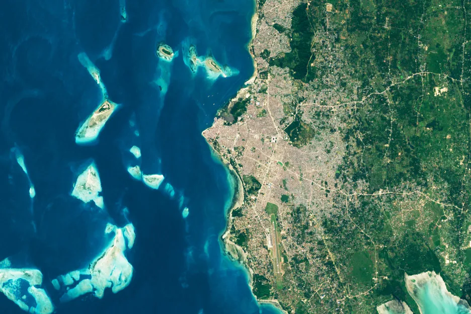 Vista de satélite da costa oeste de Unguja, com a cidade, a pista e os recifes no mar.